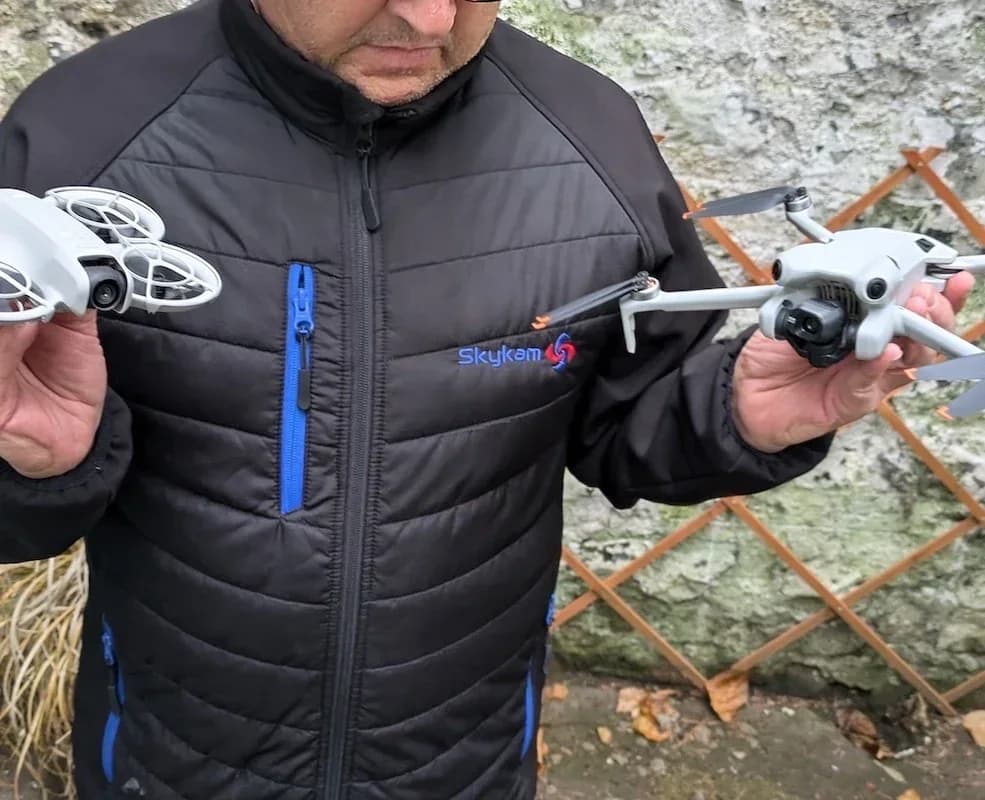 Person holds DJI Neo in one hand and another drone in the other