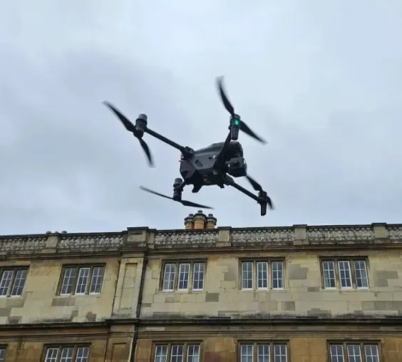 Drone conducting residential roof survey over traditional UK building