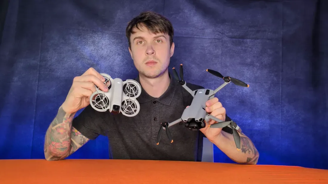 Peter Leslie holding a DJI Neo 2 in one hand and a folding DJI Mini in the other — 19 minutes of flight time against 38